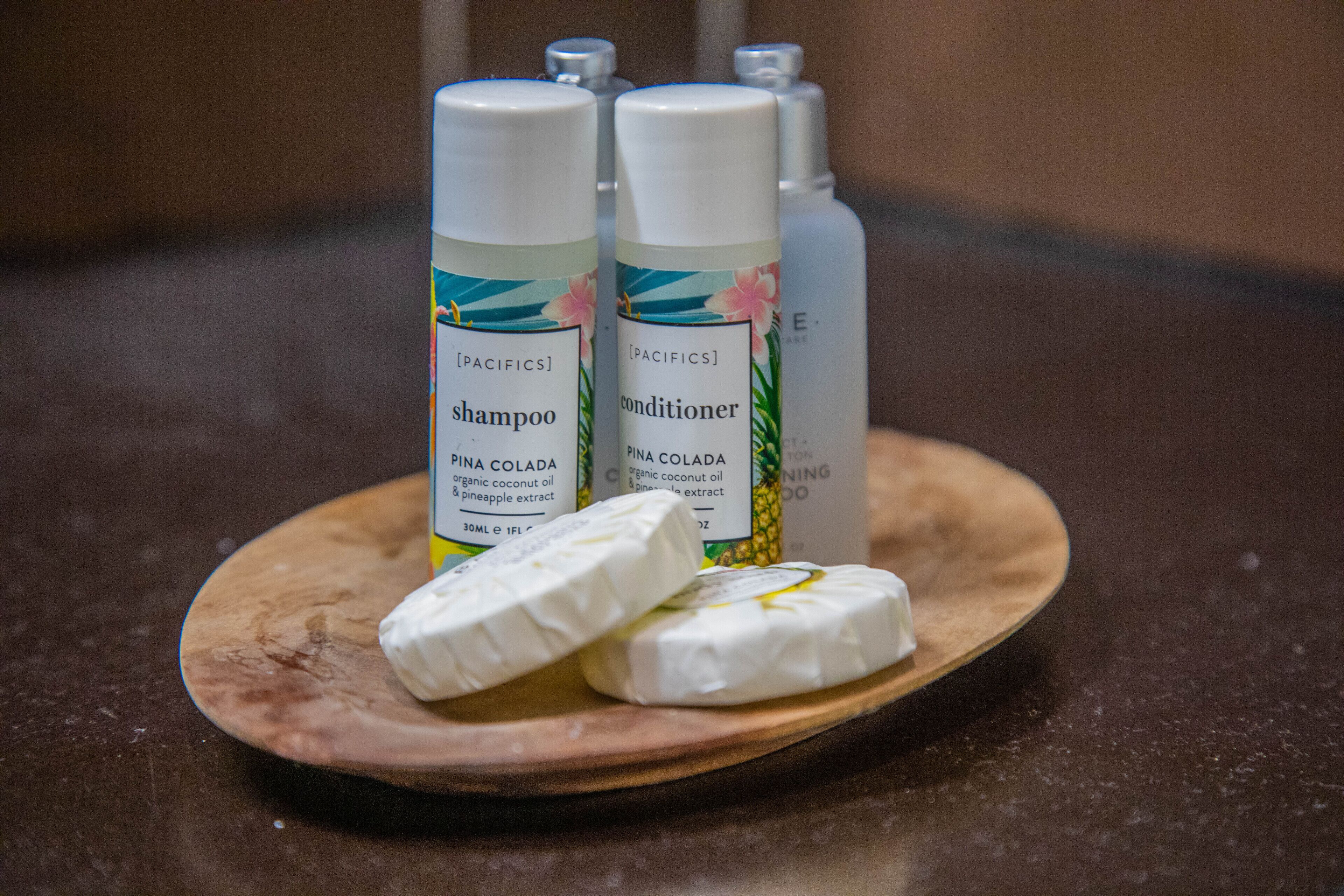 Two bottles of shampoo and conditioner on a wooden tray with two bars of soap.