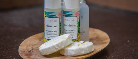 Two bottles of shampoo and conditioner on a wooden tray with two bars of soap.
