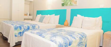 A hotel room with two beds, a wardrobe, a small table, and a wall-mounted air conditioner.