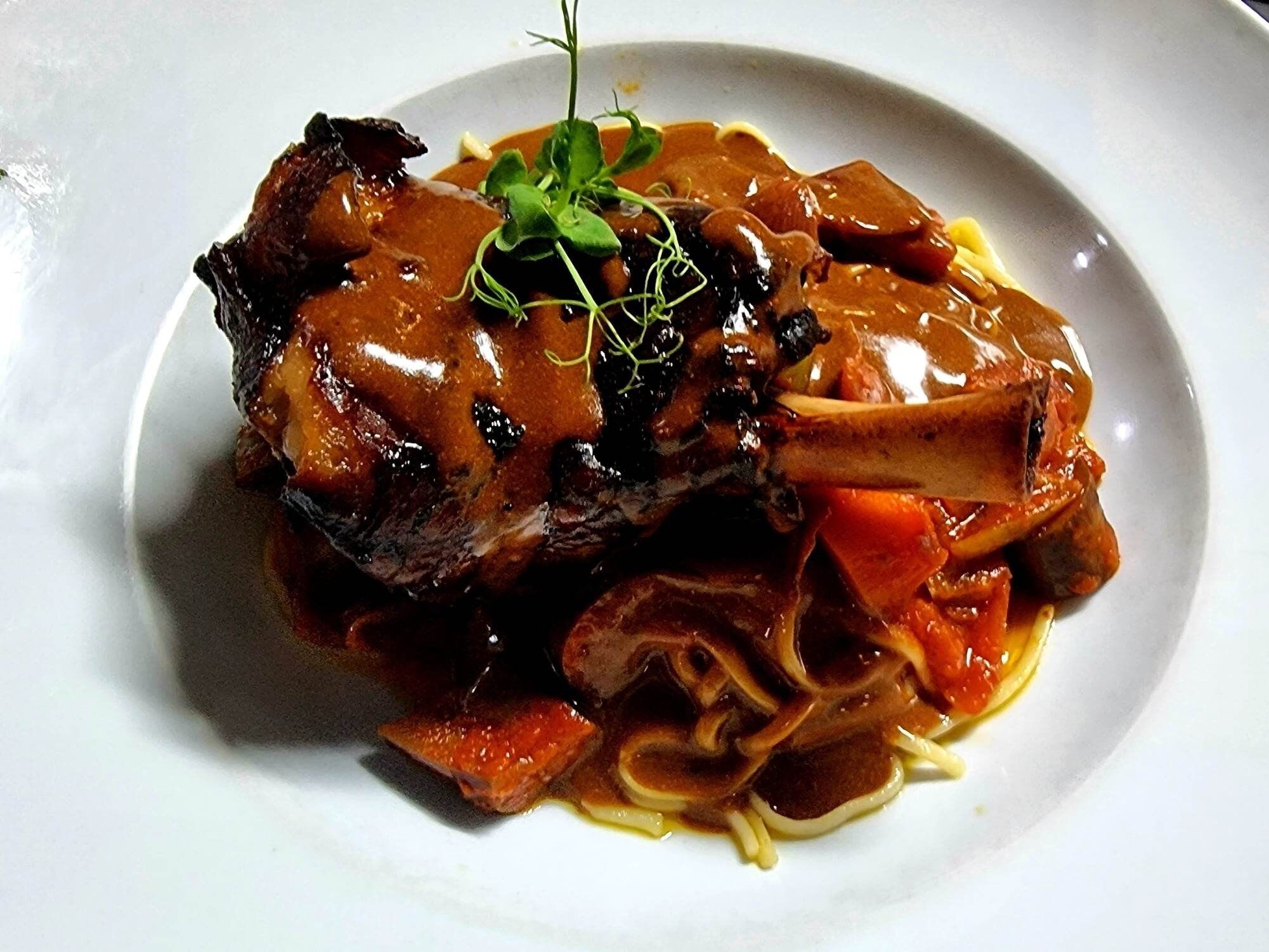 Un plato de comida con un guiso de carne, verduras y salsa.