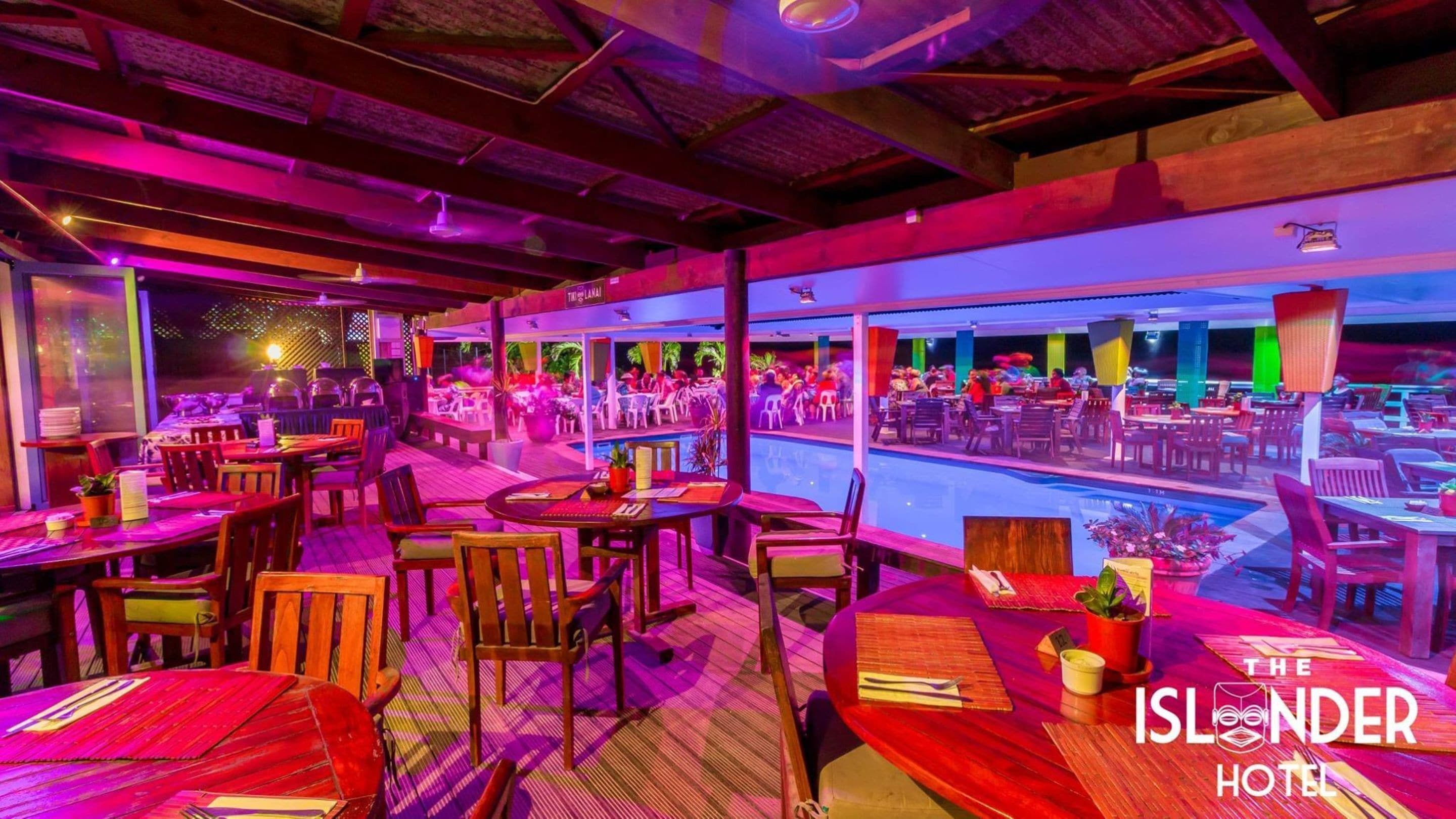 En restaurang med träbord och stolar, ett poolomr åde och utsikt över poolen.