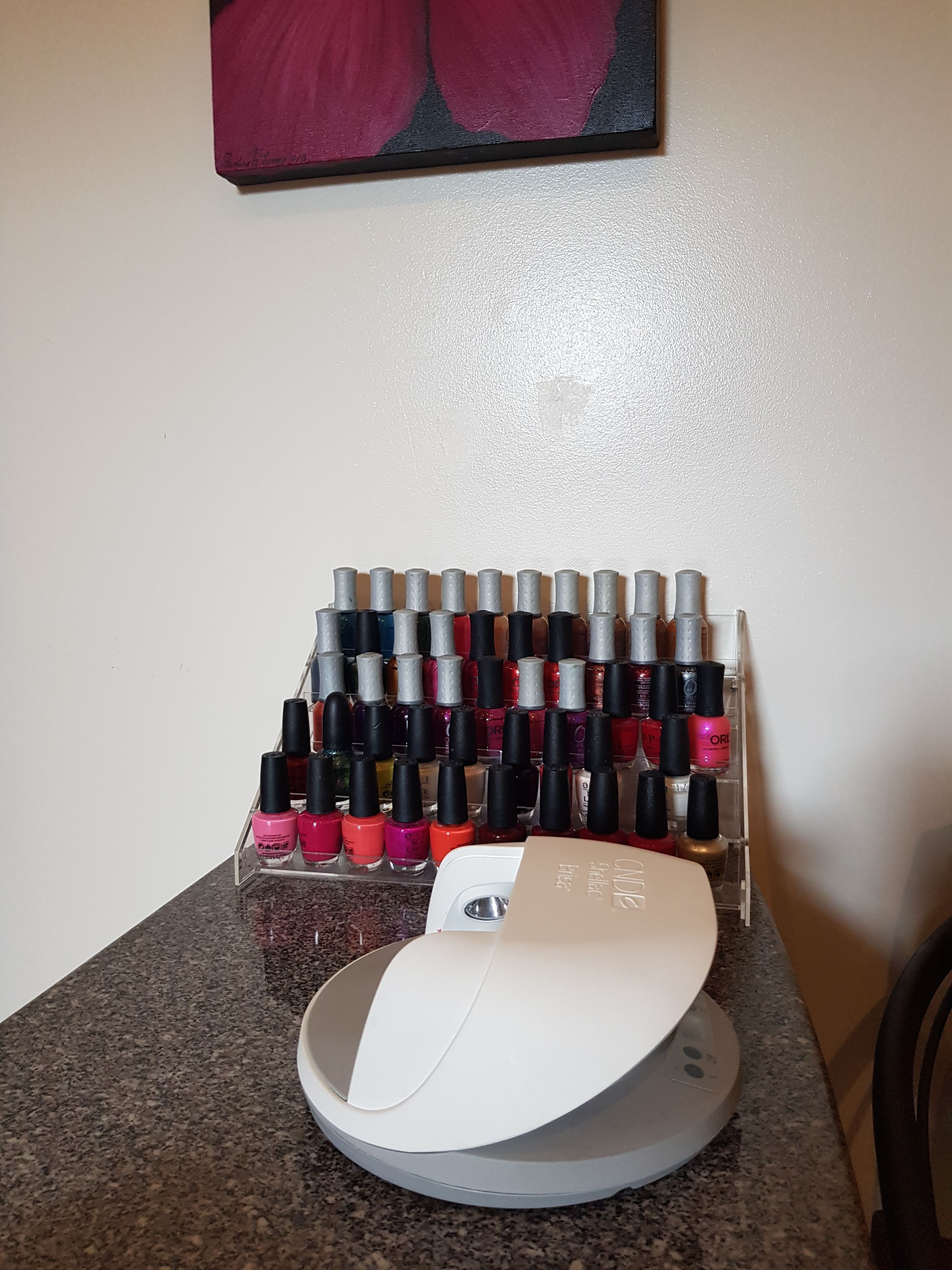 Un rangement pour vernis à ongles contenant plusieurs flacons, posé sur un comptoir.