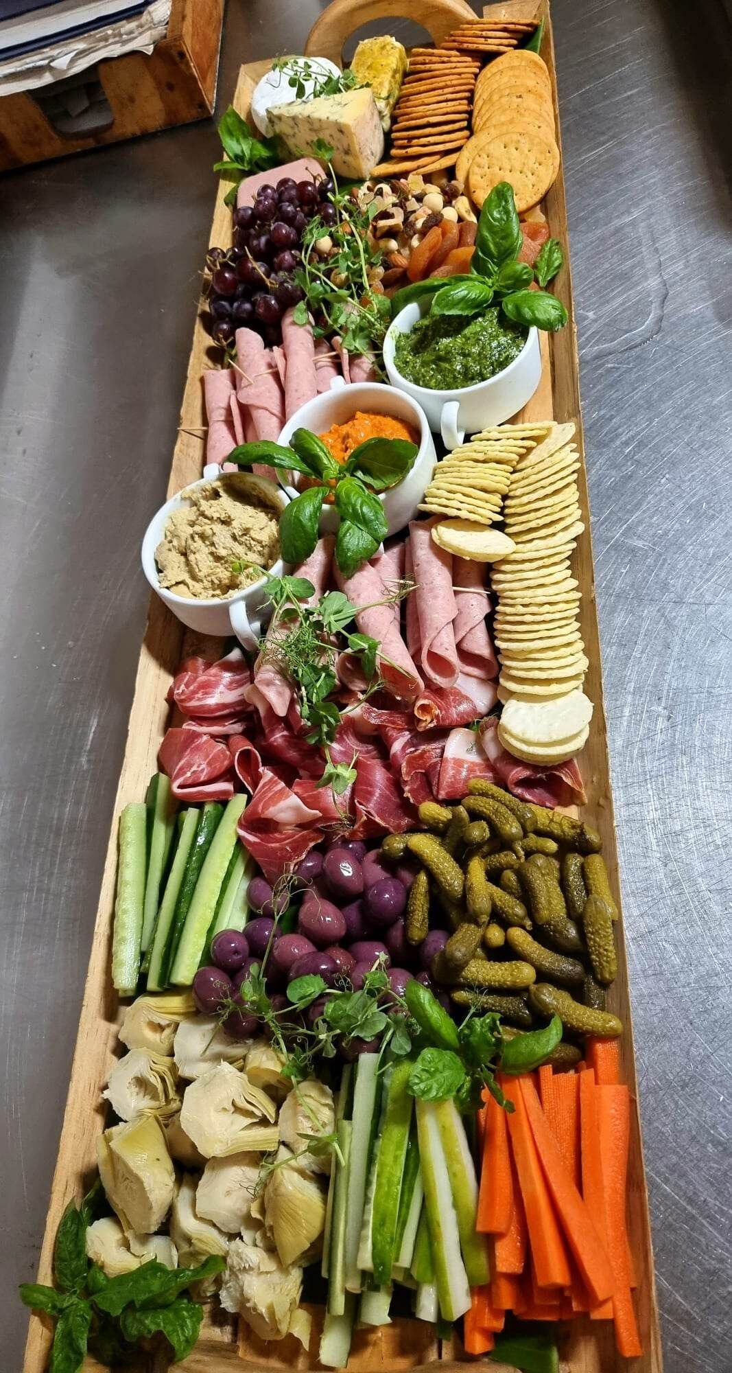 Ein Holzbrett mit verschiedenen Speisen, darunter Fleisch, Käse und Gemüse.