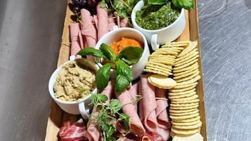 Una taula de fusta amb diferents aliments, com ara carns, formatges i verdures.