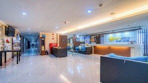 Hall d'albergo con reception, area relax e corridoio che porta ad altre camere.