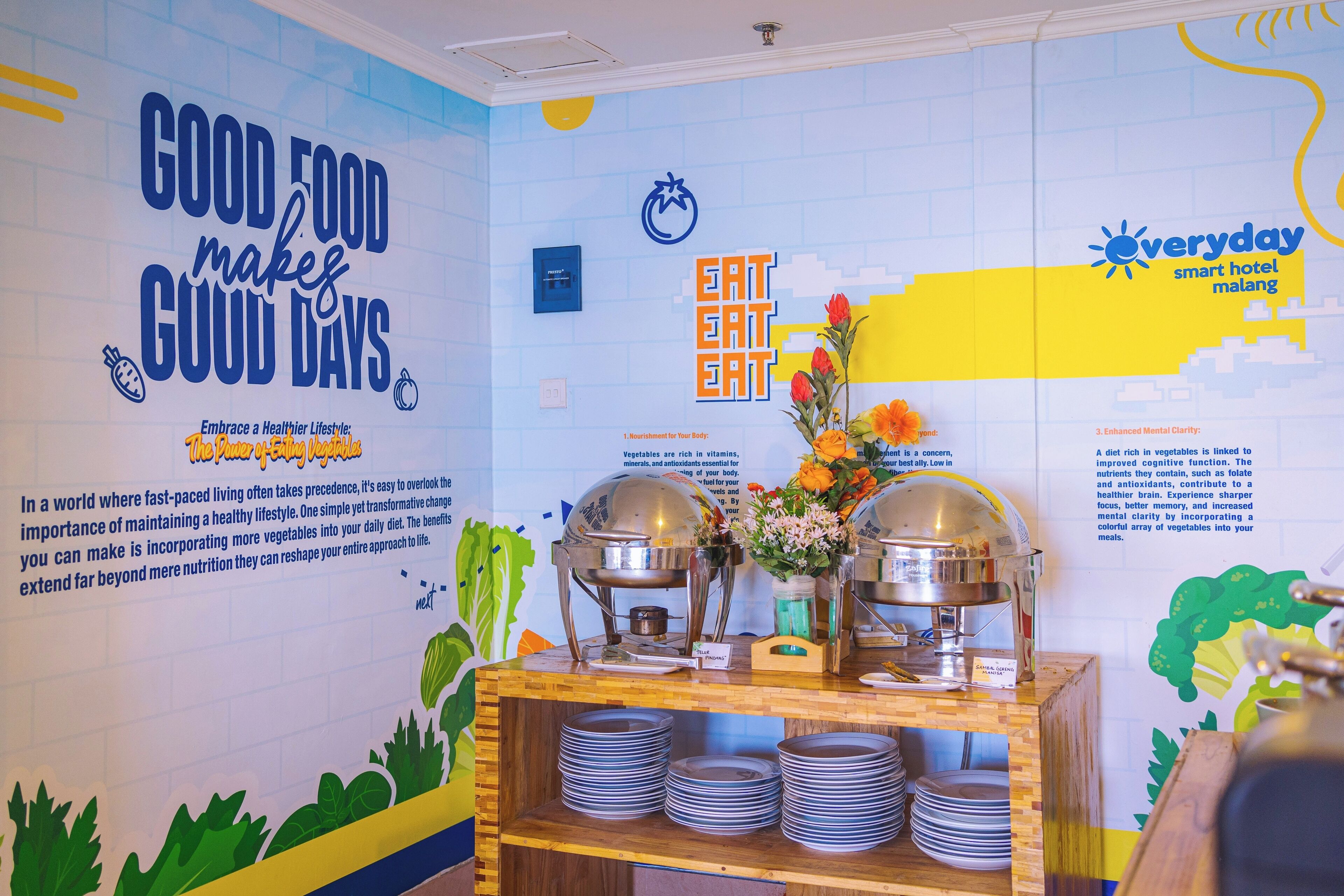 Un buffet agrémenté d’une fresque murale encourageant une alimentation saine, d’un saladier rempli de fruits et d’une variété de plats.
