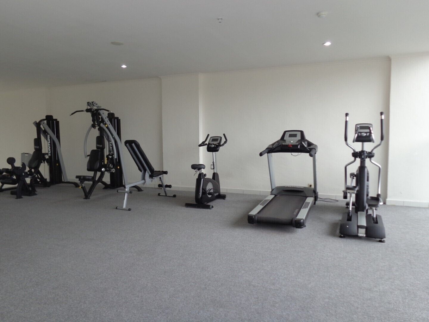A gym with various exercise equipment including a treadmill, stationary bikes, and weight machines.