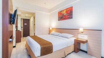 A hotel room with a large bed, bedside tables with lamps, a wooden headboard, a painting on the wall, and a wardrobe.