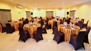 Una sala conferenze con diversi tavoli rotondi, ognuno con sedie, bottiglie d'acqua e cartellini.
