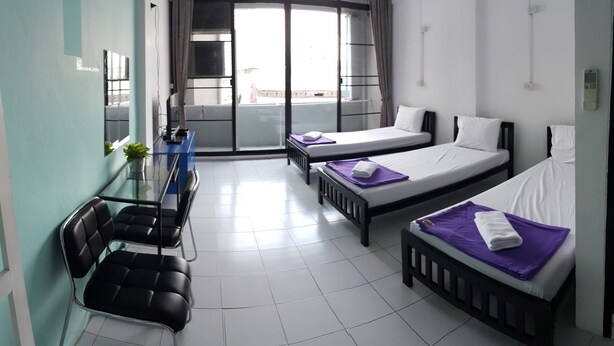 A hotel room with two beds, a small table, a chair, and a balcony with a view. - de Talak (Bangkok)