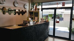 A reception area with a black counter, multiple clocks, and a large glass door leading outside. - de Talak (Bangkok)