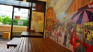 An interior with a wooden bench, a mural depicting a street scene, and a vending machine. - de Talak (Bangkok)