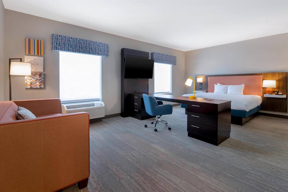 Une chambre d’hôtel équipée d’un lit, d’un bureau, d’une chaise et d’un téléviseur.