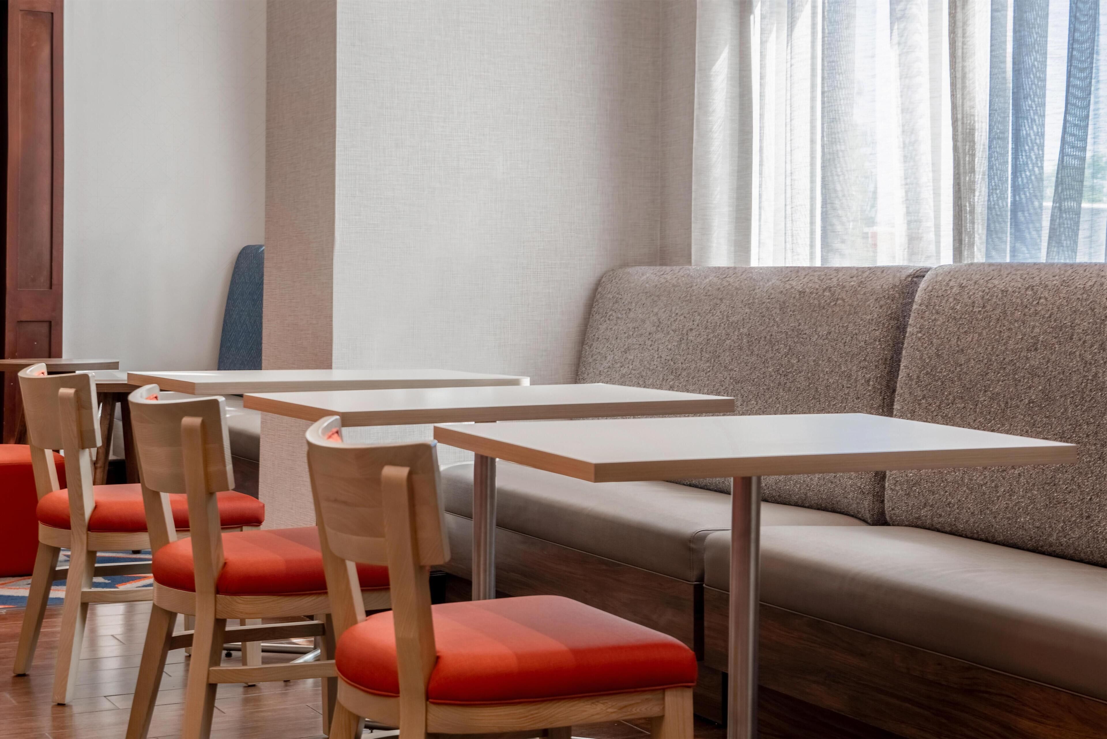 A modern interior with a sofa, wooden chairs, and tables.