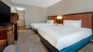 A hotel room with two beds, a TV, a desk, and a wardrobe.