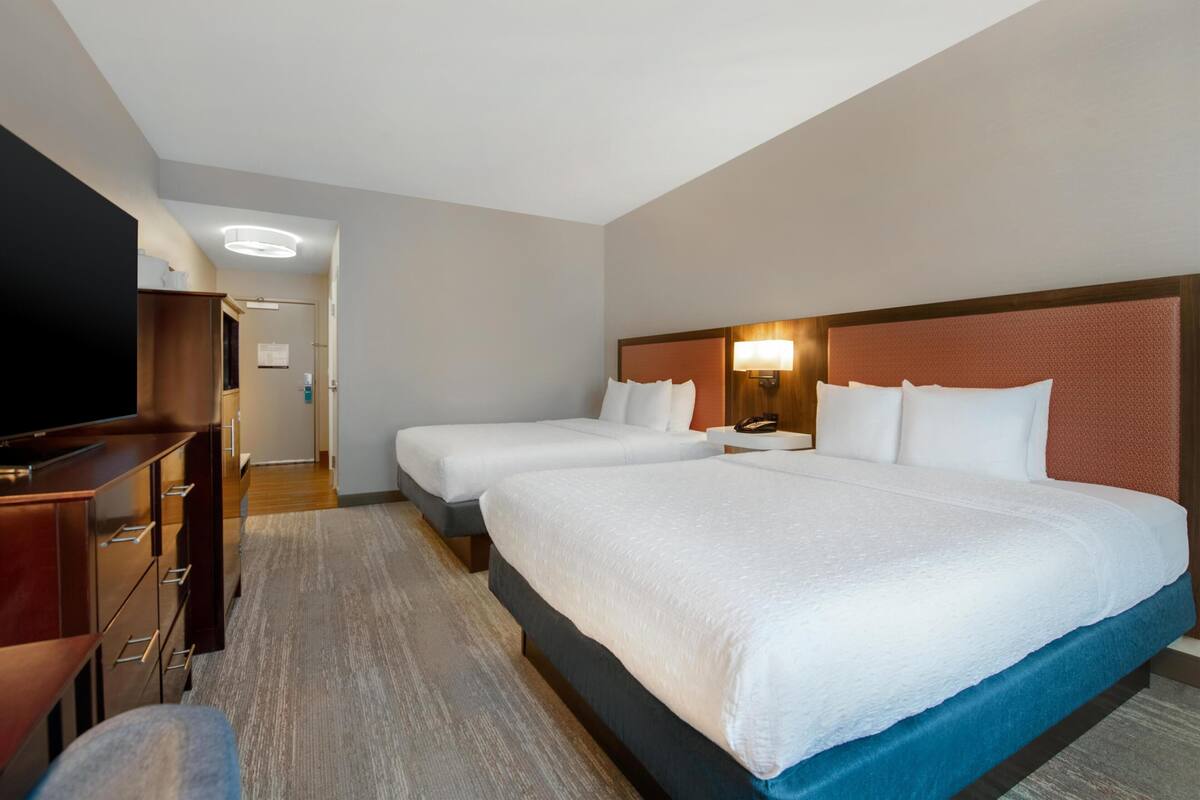 Une chambre d’hôtel avec deux lits, une télévision, un bureau et une armoire.