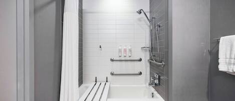 A modern bathroom with a walk-in shower, grab bars, and a white bathtub.