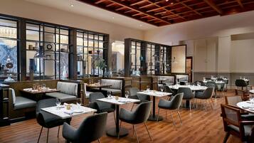 A restaurant with wooden flooring, tables, and chairs arranged for dining.