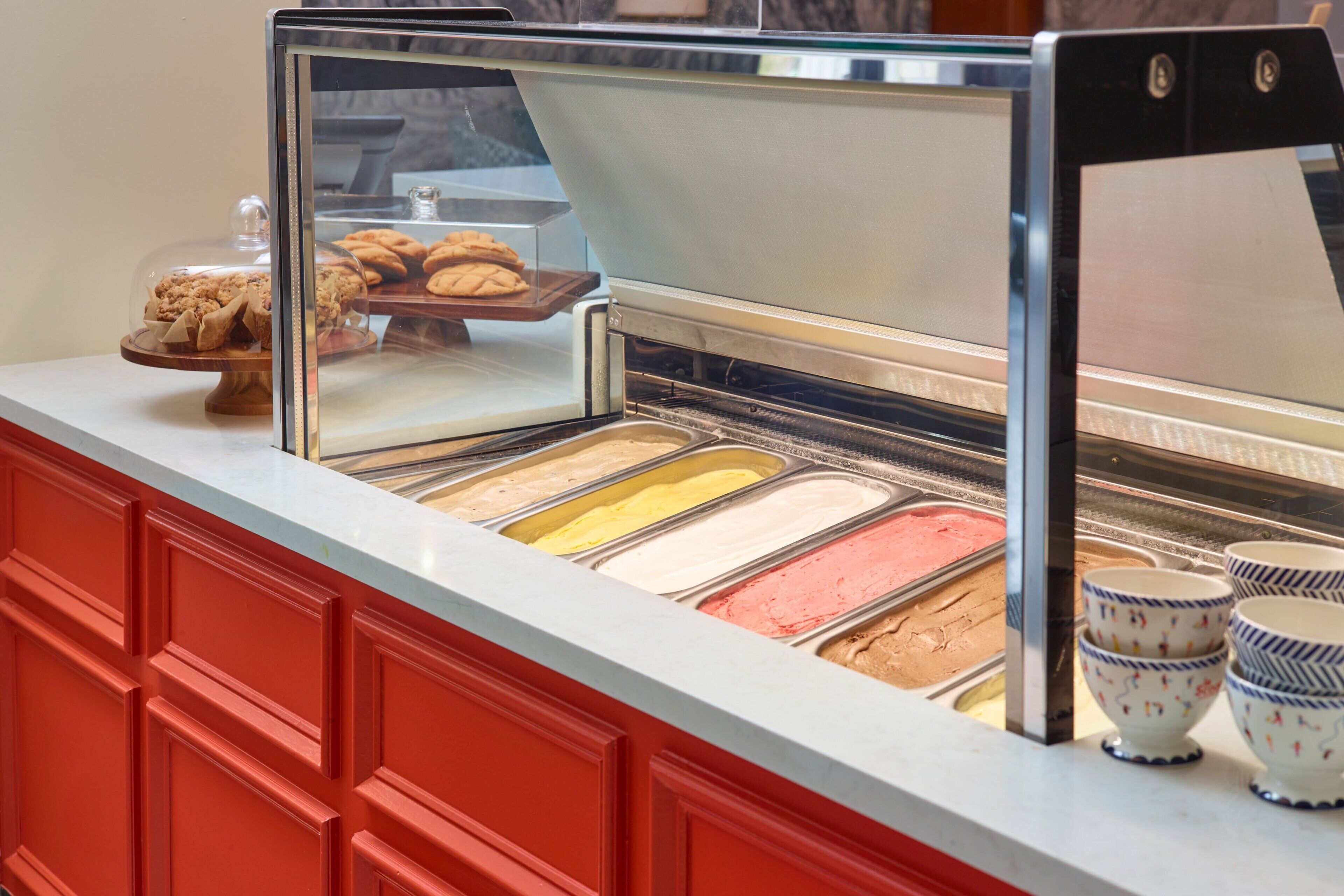 A self-serve ice cream bar with multiple flavors and a display of cookies.