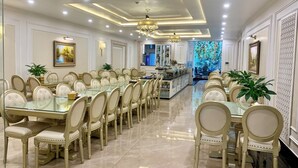 A spacious dining area with a long table, multiple chairs, and a central chandelier. - Hoang Hai Hotel (Hai Phong)