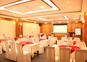 A conference room with multiple tables, chairs, and a presentation screen.