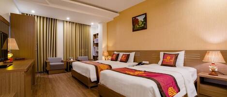 A hotel room with two beds, a desk, a chair, and a TV.