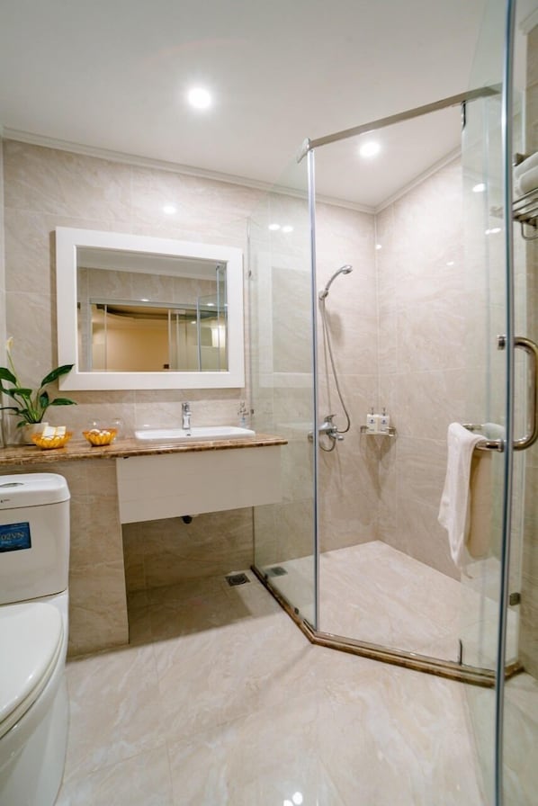 A modern bathroom with a glass-enclosed shower, a white sink, and a mirror above the sink.