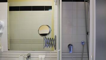 A bathroom with a white sink, a mirror, a towel rack, and a shower enclosure.