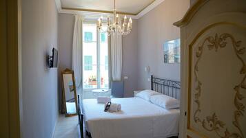 Een hotelkamer met een groot bed, een kroonluchter, een spiegel en uitzicht op de stad.