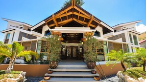 A modern building with a wooden gable roof, large windows, and a stone pathway leading to the entrance.