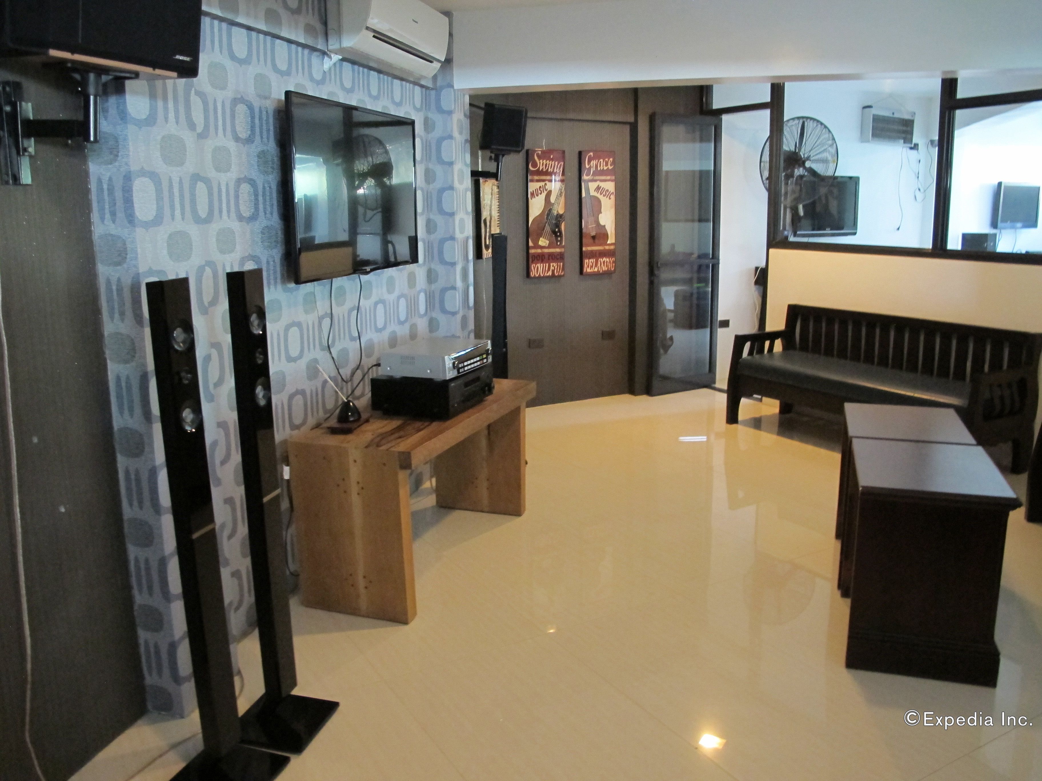 A modern living room with a flat-screen TV, a wooden bench, a small table with a speaker, and a poster on the wall.