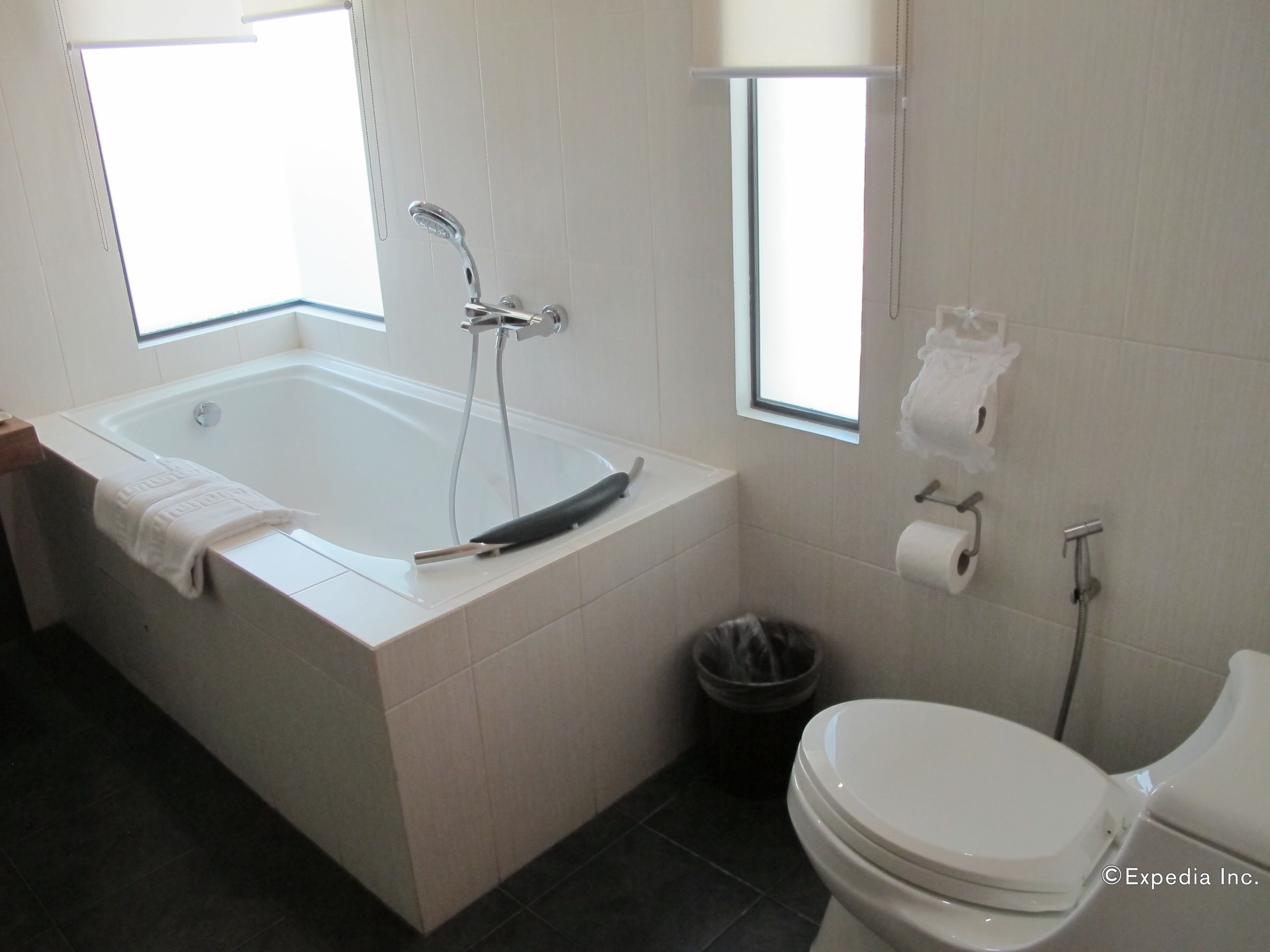 A modern bathroom with a bathtub, toilet, and a window providing natural light.
