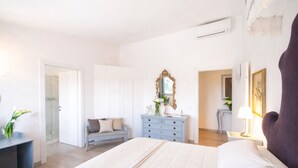 Un dormitorio con cama, cómoda, espejo y una puerta que da a otra habitación.