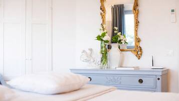 A bedroom with a bed, a dresser with a mirror, and a vase with flowers.