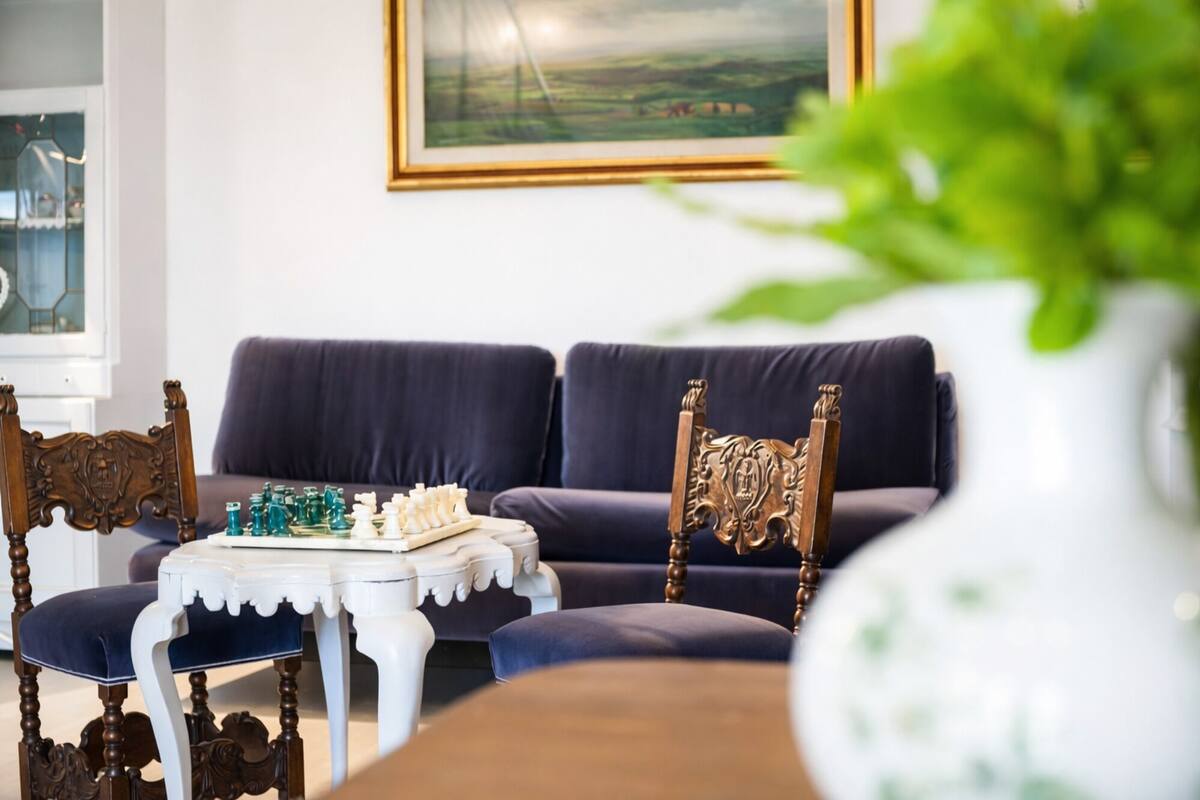 A living room with a sofa, a chess table, and a decorative chair.
