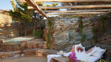 Relax in a serene outdoor oasis with a hot tub, bench, and lush greenery.