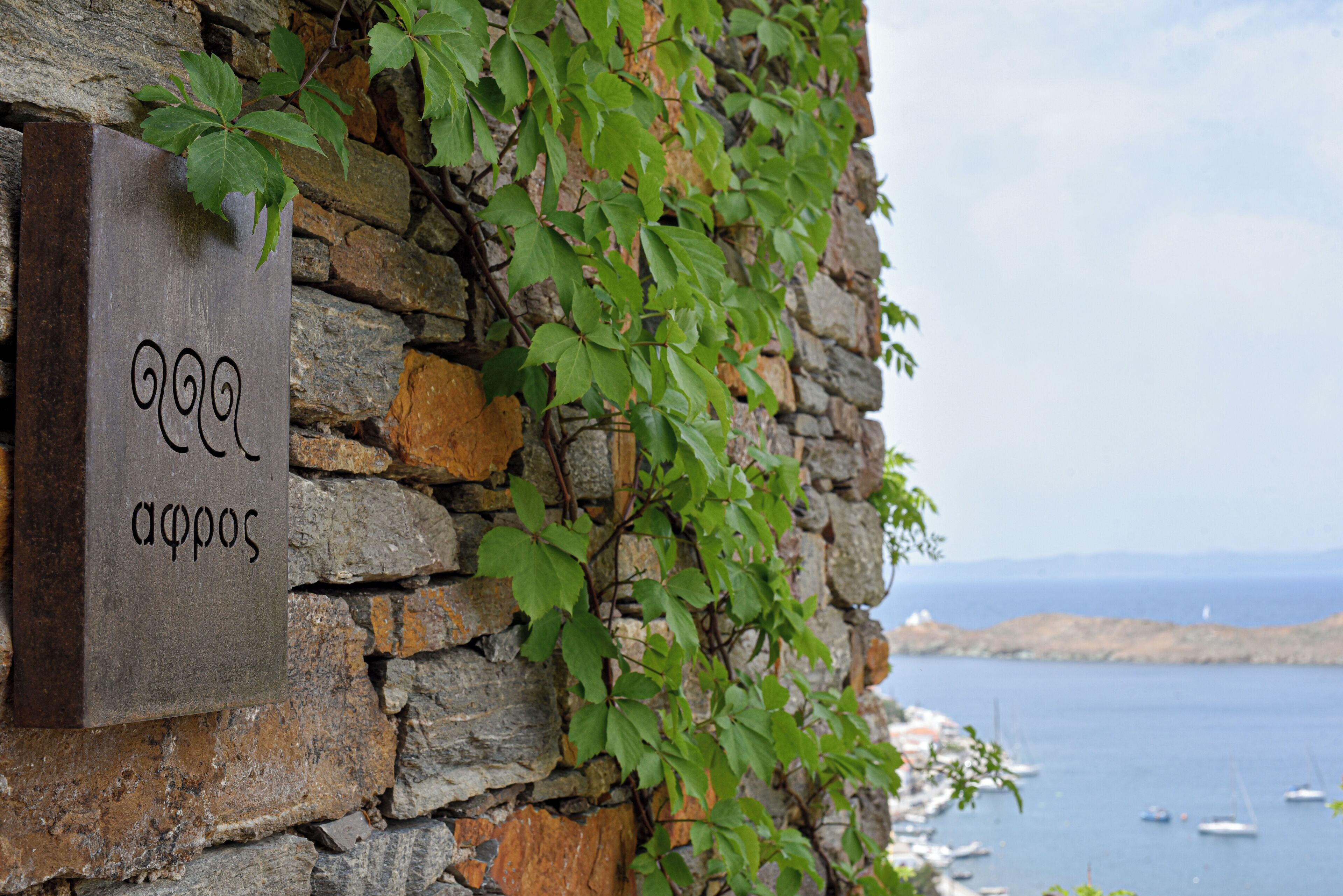 A stone wall with a sign and green foliage.