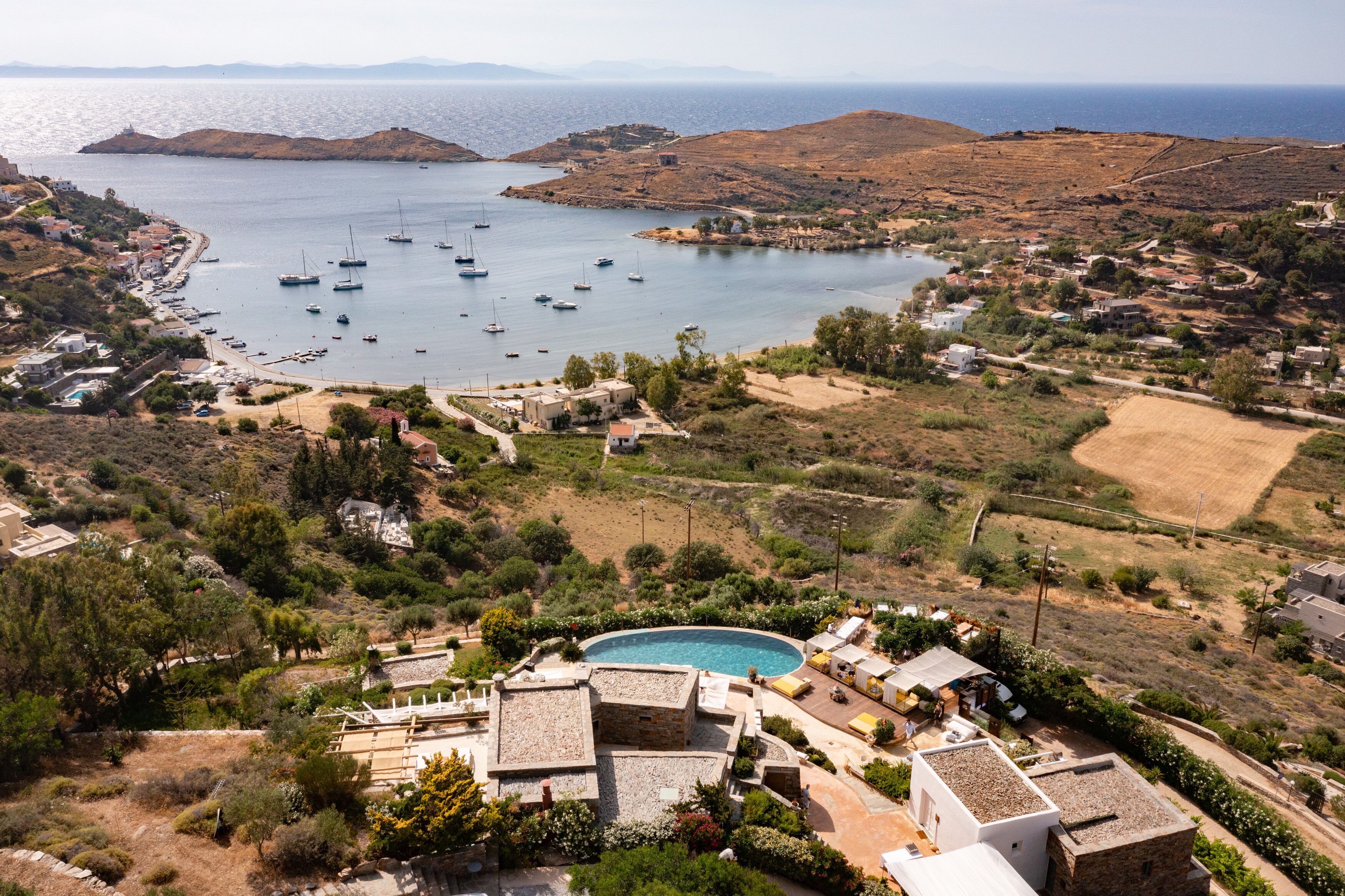 A coastal village with a swimming pool, boats, and a view of the sea.