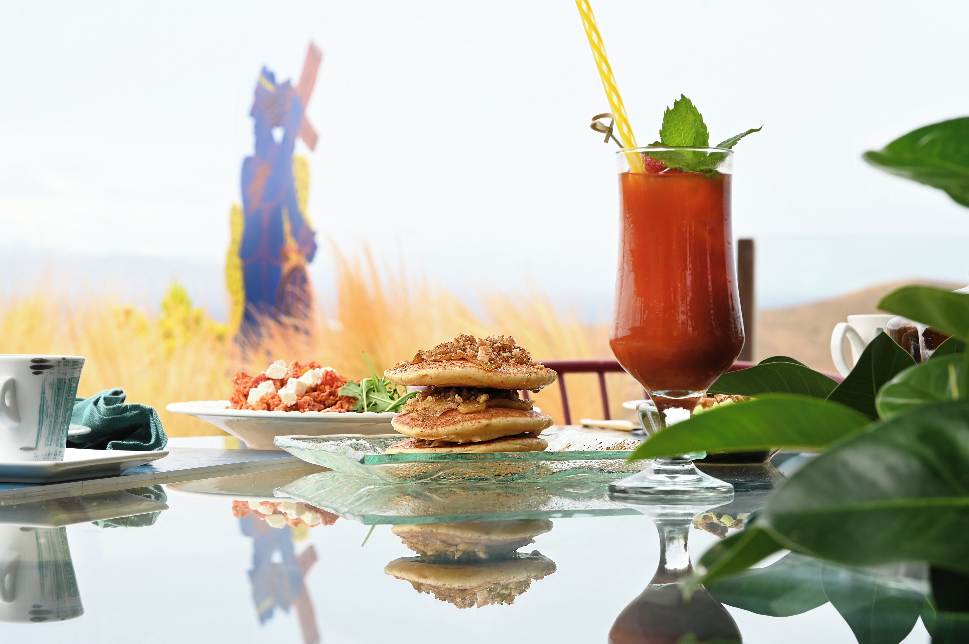 A table with a glass of iced tea, a cup, and a plate of food.