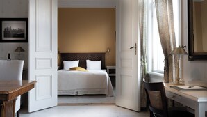 A hotel room with a bed, a desk, a chair, and a window with curtains.