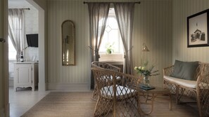 A room with a desk, wicker chairs, a sofa, a mirror, curtains, and a framed picture on the wall.