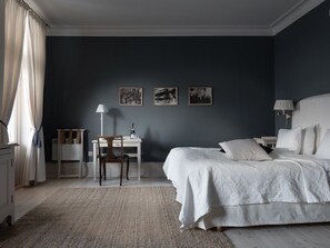 A bedroom with a bed, a desk, a chair, and three framed pictures on the wall.