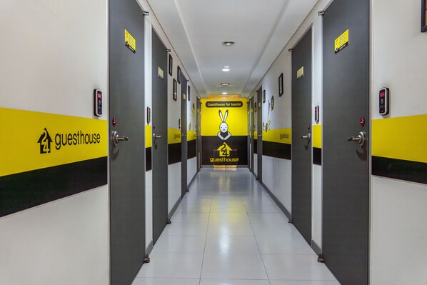 A hotel corridor with doors labeled "Guesthouse for tourist" and a central wall with a rabbit logo.