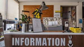 Een receptiebalie met een bord waarop 'INFORMATION' staat en een nummer 24 in de achtergrond.