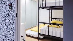 Een slaapkamer met stapelbedden, een muur met zebrapatroon, een bedieningspaneel en een schuifdeur.