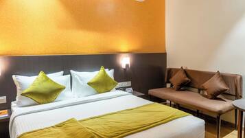 A hotel room with a bed, a bench, and a wall-mounted air conditioner.