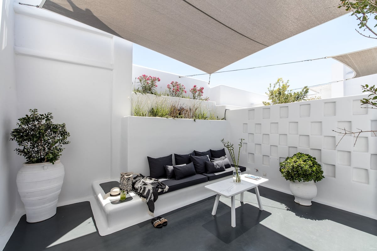 A modern, minimalist living space with a white sofa, a coffee table, and potted plants.