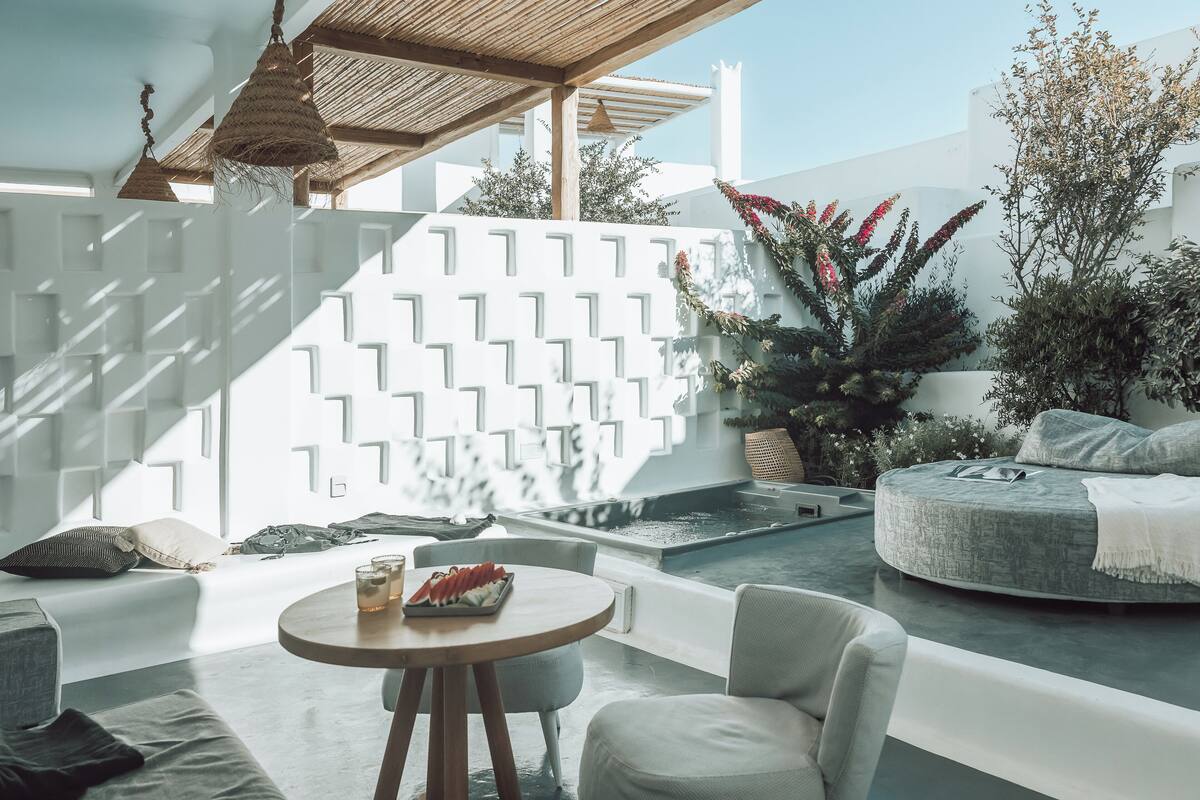 A modern outdoor seating area with a round table, cushioned seating, and a decorative wall with geometric patterns.