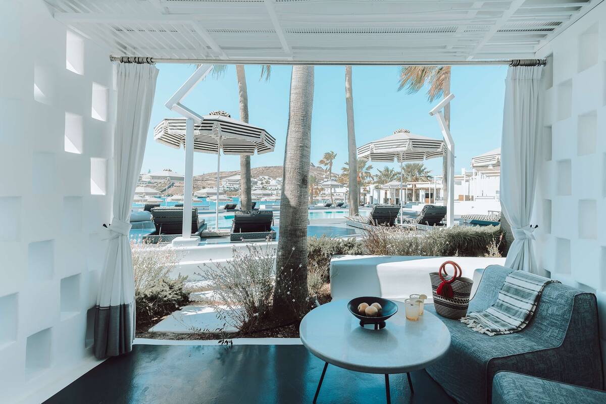 A modern lounge area with a view of a pool and palm trees.