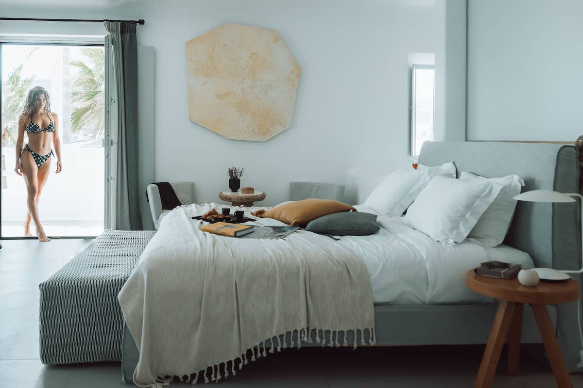 A modern bedroom with a bed, bedside table, and a view of the outdoors.